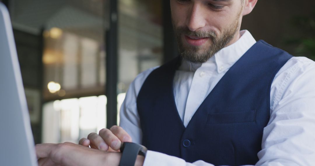 Businessman in Blue Vest Checking Smartwatch While Working - Free Images, Stock Photos and Pictures on Pikwizard.com