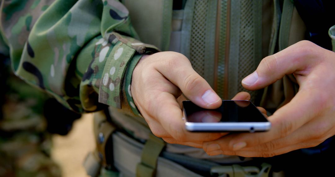 Soldier in camouflage uniform using smartphone in field - Free Images, Stock Photos and Pictures on Pikwizard.com