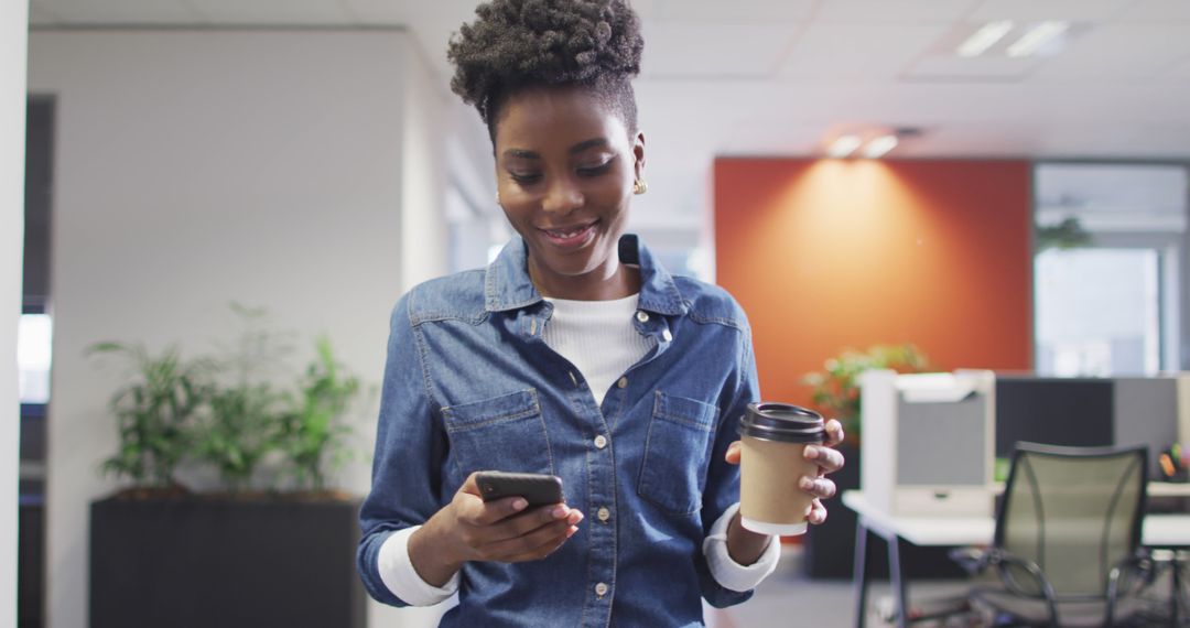 Smiling African American Woman Drinking Coffee and Using Smartphone in Office - Free Images, Stock Photos and Pictures on Pikwizard.com