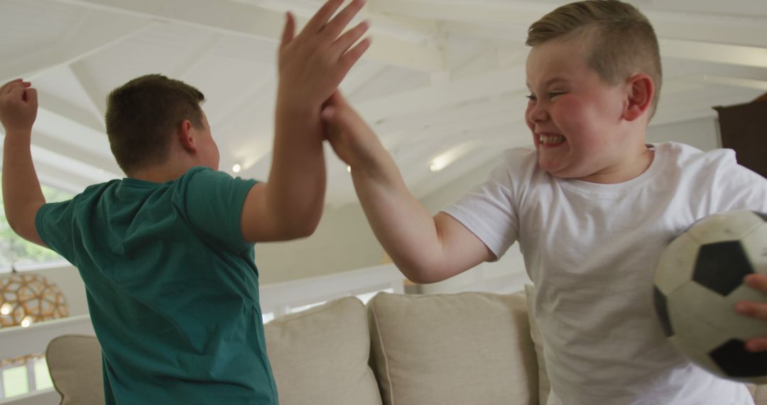 Two Boys Playfully Fighting in Modern Living Room with Soccer Ball - Free Images, Stock Photos and Pictures on Pikwizard.com