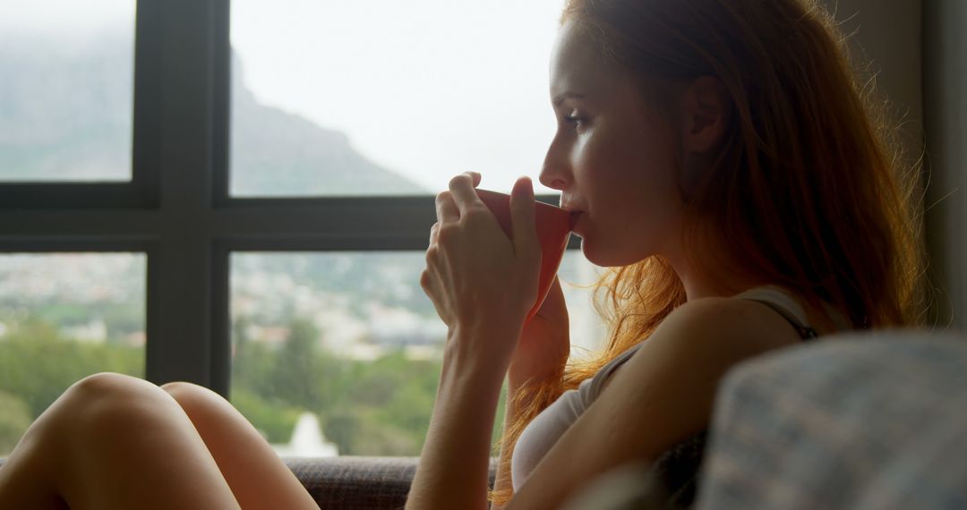 Woman Relaxing Indoors Drinking Coffee by Window - Free Images, Stock Photos and Pictures on Pikwizard.com