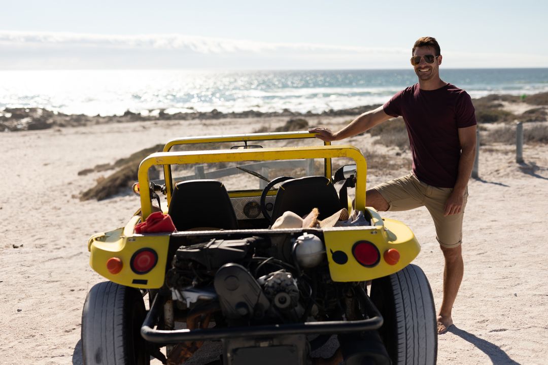 Man Enjoying Ocean View with Yellow Dune Buggy on Sunny Beach