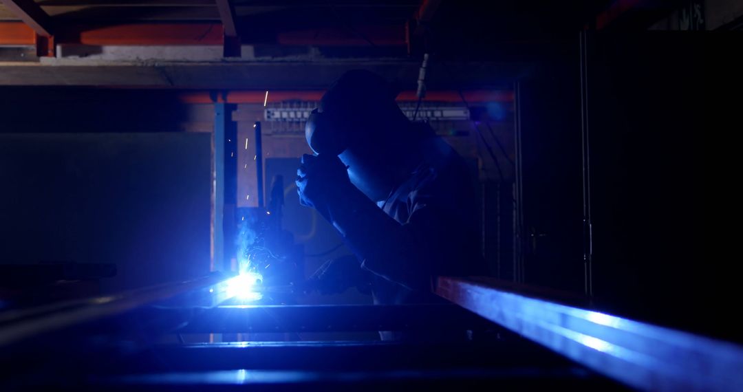 Welder Working with Bright Blue Torch in Low Light Industrial Workshop - Free Images, Stock Photos and Pictures on Pikwizard.com