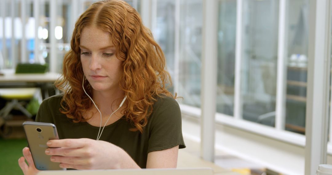 Young Woman Concentrating on Smartphone in Modern Office Environment - Free Images, Stock Photos and Pictures on Pikwizard.com