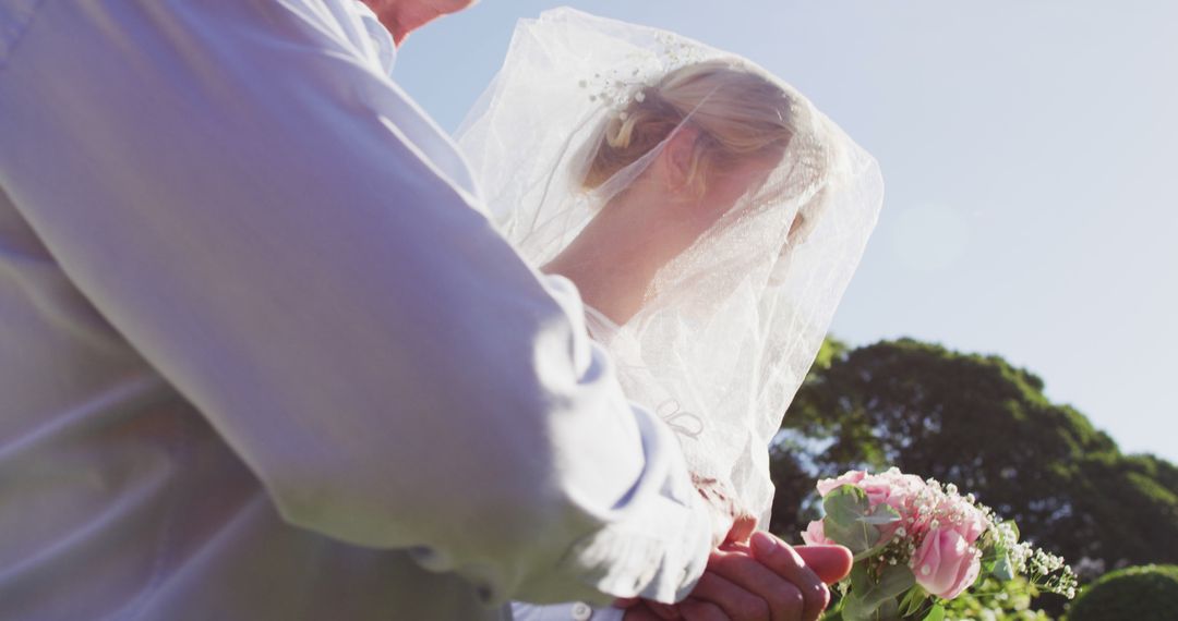 Bride Holding Bouquet with Veil Blowing in the Wind Outdoors - Free Images, Stock Photos and Pictures on Pikwizard.com