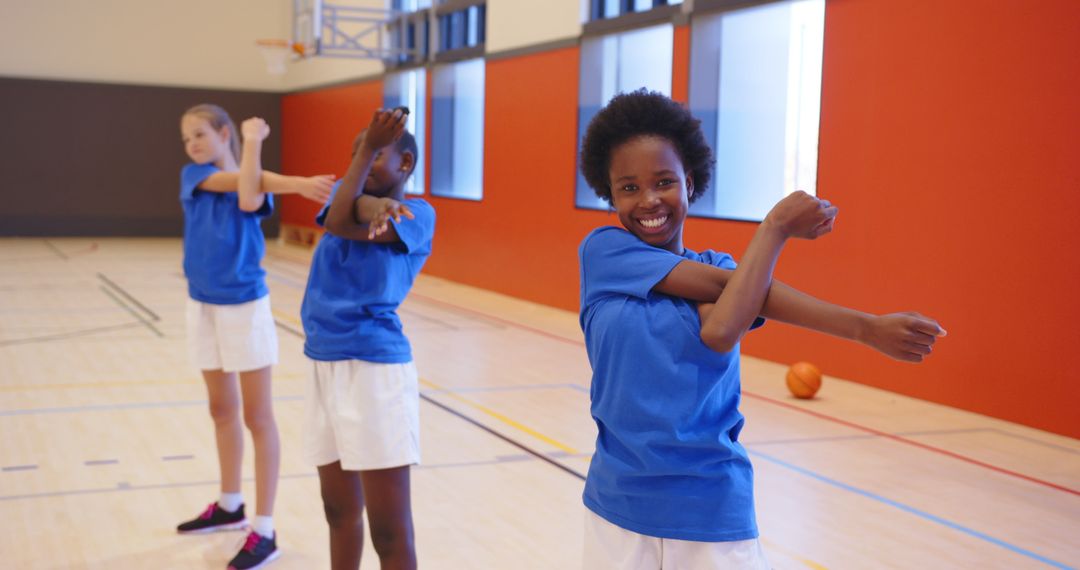Diverse Schoolgirls Stretching in Gym for Basketball Practice