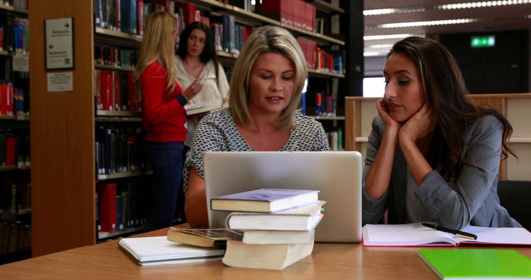 Two Women Studying Together in Library, Laptop and Books on Table - Free Images, Stock Photos and Pictures on Pikwizard.com