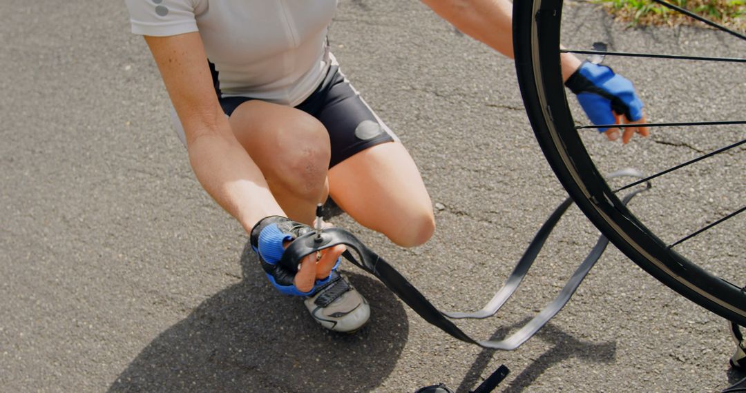 Cyclist Fixing Flat Tire on Roadside in Sunlight - Free Images, Stock Photos and Pictures on Pikwizard.com