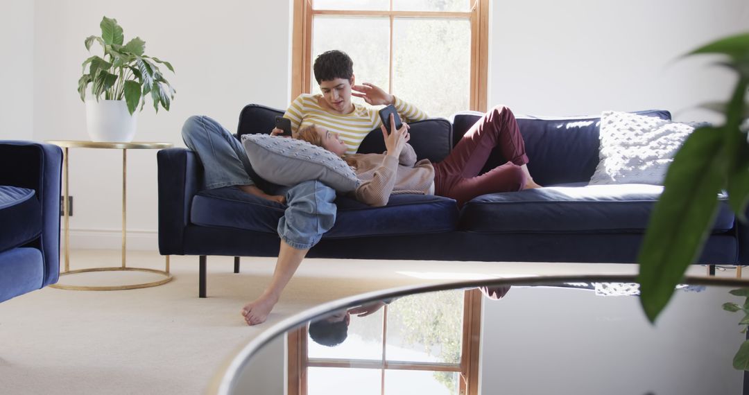 Couple Relaxing on Sofa Using Tablet and Phone in Sunlit Home