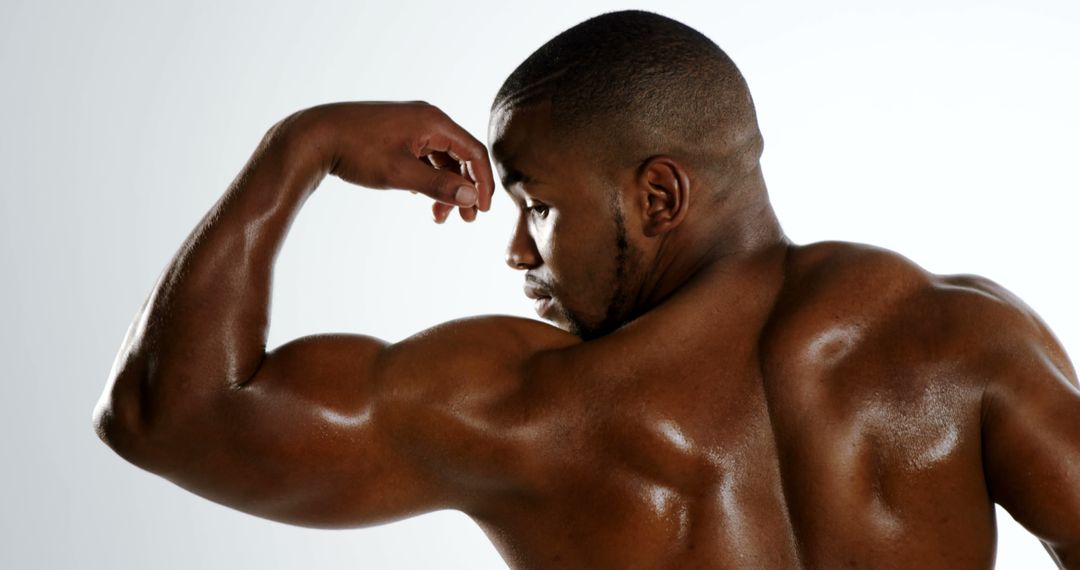 An African American man showcases his muscular physique by flexing his bicep, with copy space - Free Images, Stock Photos and Pictures on Pikwizard.com