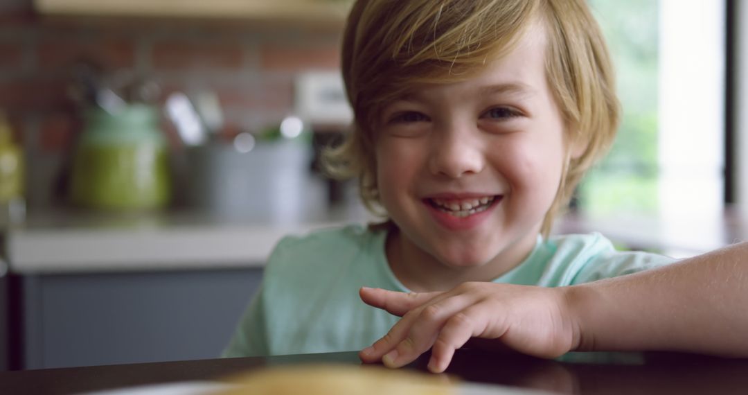 Smiling Child Sitting at Kitchen Table - Free Images, Stock Photos and Pictures on Pikwizard.com