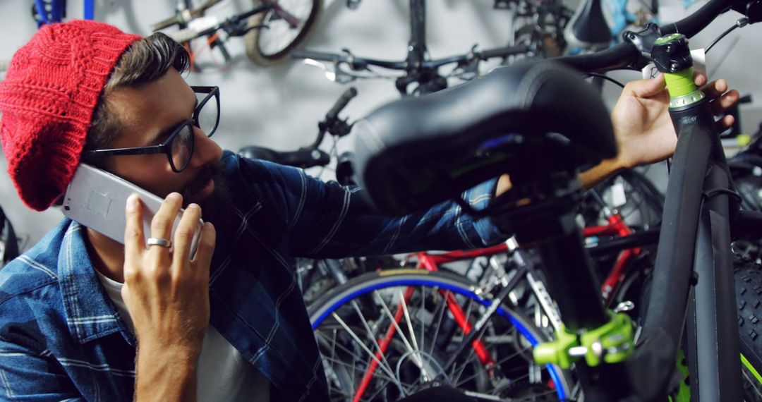 Man Repairing Bicycle While Talking on Phone in Workshop - Free Images, Stock Photos and Pictures on Pikwizard.com