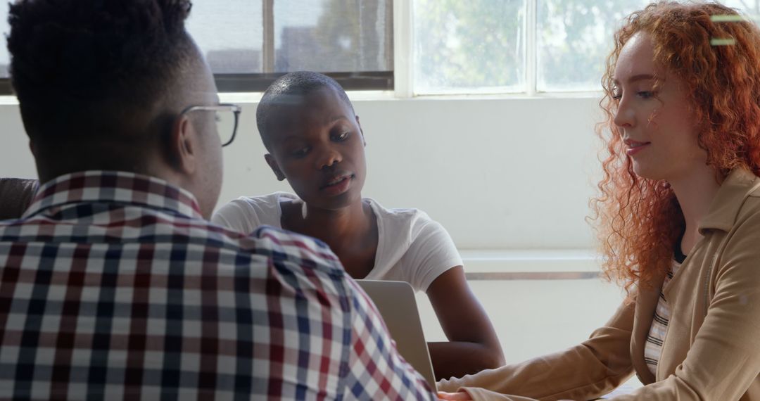 Diverse Team Collaborating Over Laptop in Bright Office