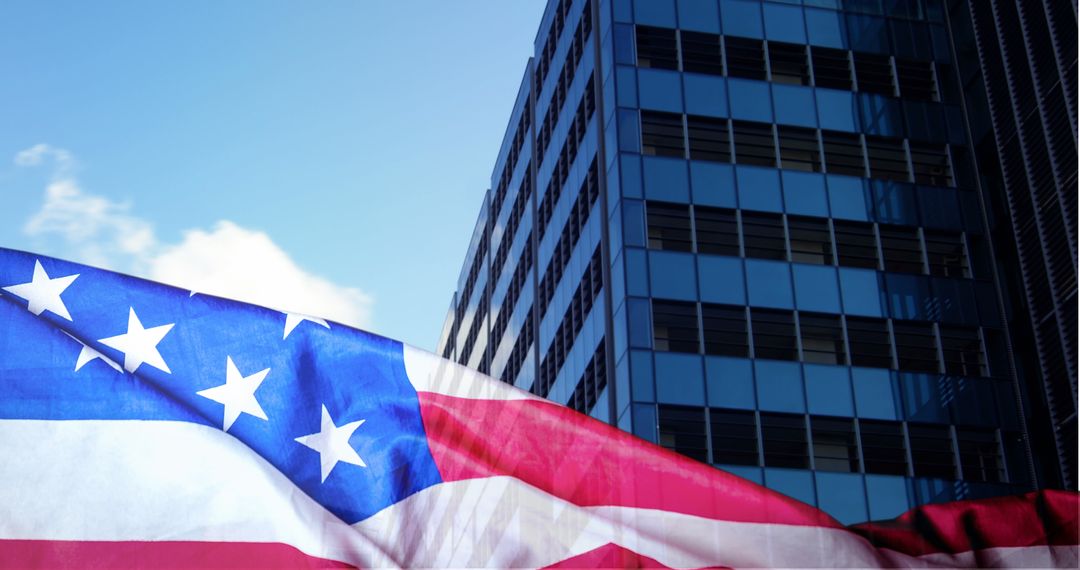 American Flag with Skyscraper Against Blue Sky and Clouds