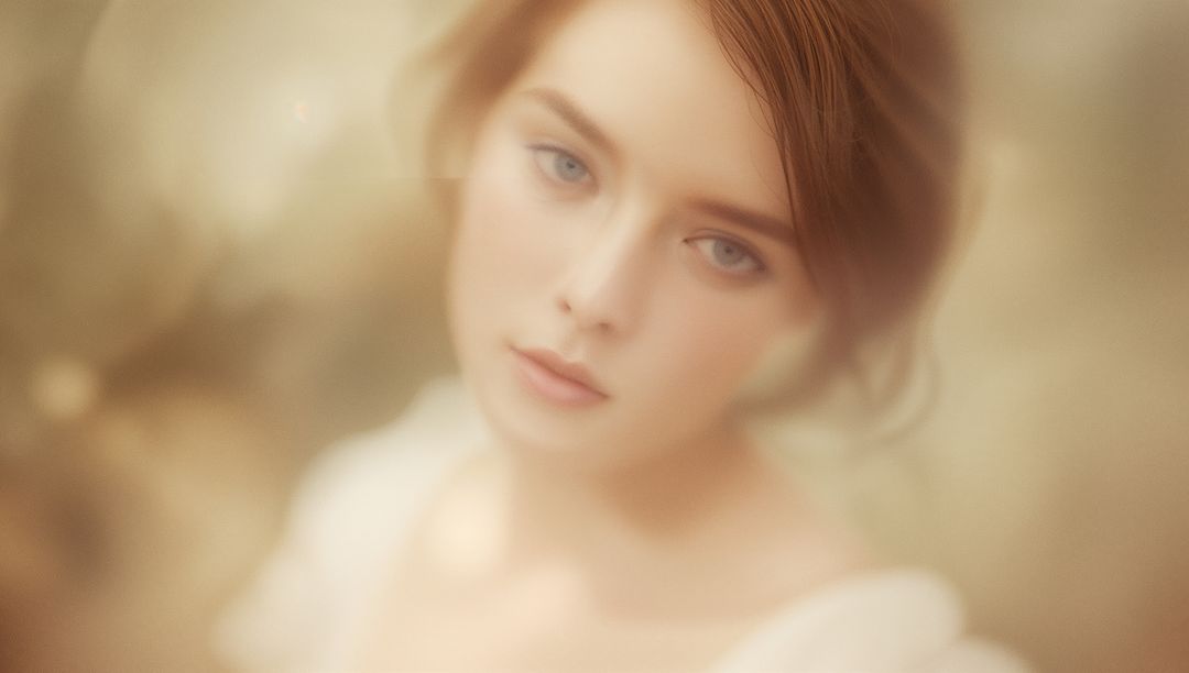 Dreamy soft-focus portrait young woman with golden bokeh glow and serene gaze