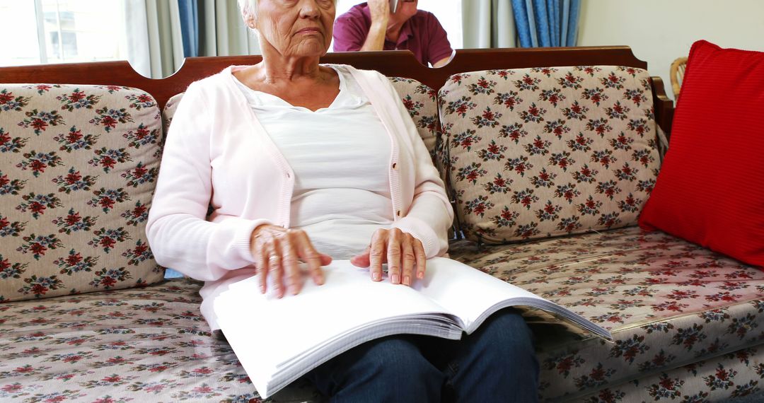 Elderly woman reading braille book while sitting on sofa - Free Images, Stock Photos and Pictures on Pikwizard.com