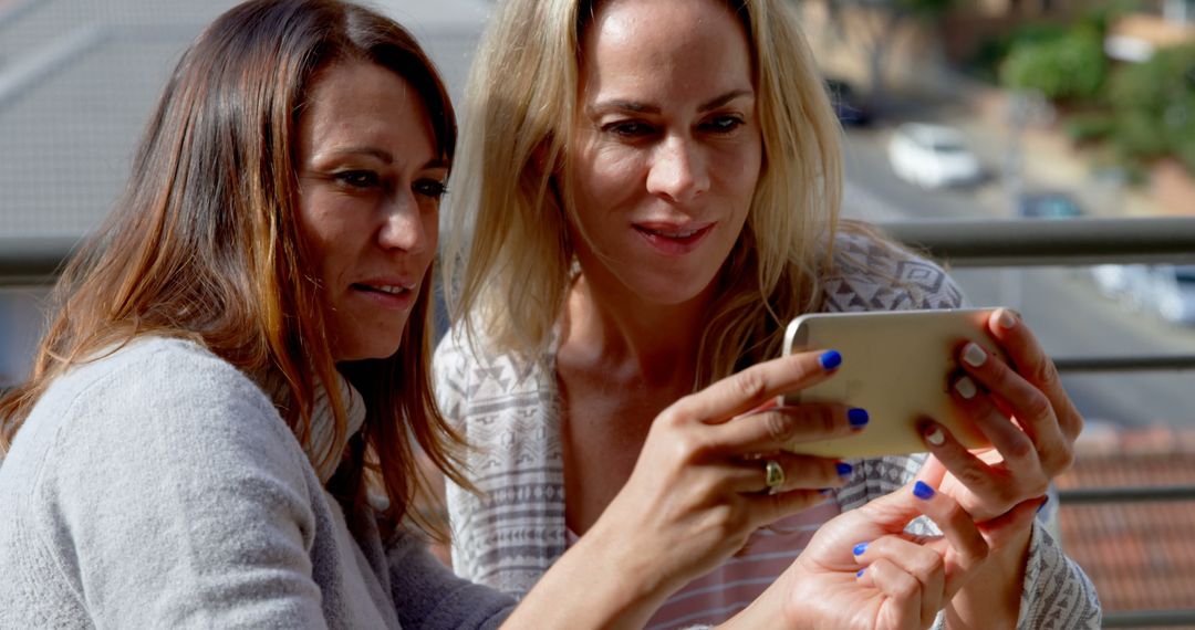 Two Women Watching Video on Smartphone Outdoors - Free Images, Stock Photos and Pictures on Pikwizard.com