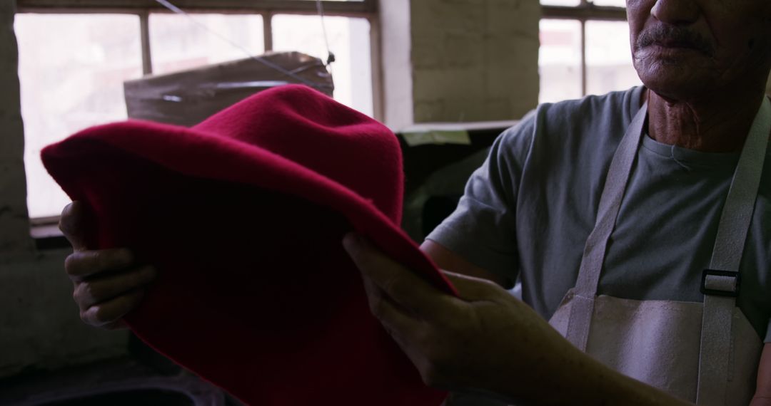 Senior Artisan Holding Red Felt Hat in Workshop - Free Images, Stock Photos and Pictures on Pikwizard.com