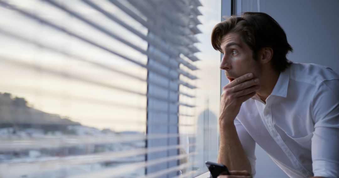 Worried Businessman Using Smartphone by Office Window