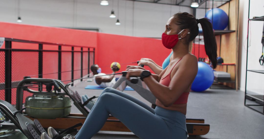 Woman Exercising on Rowing Machine with Mask in Gym - Free Images, Stock Photos and Pictures on Pikwizard.com