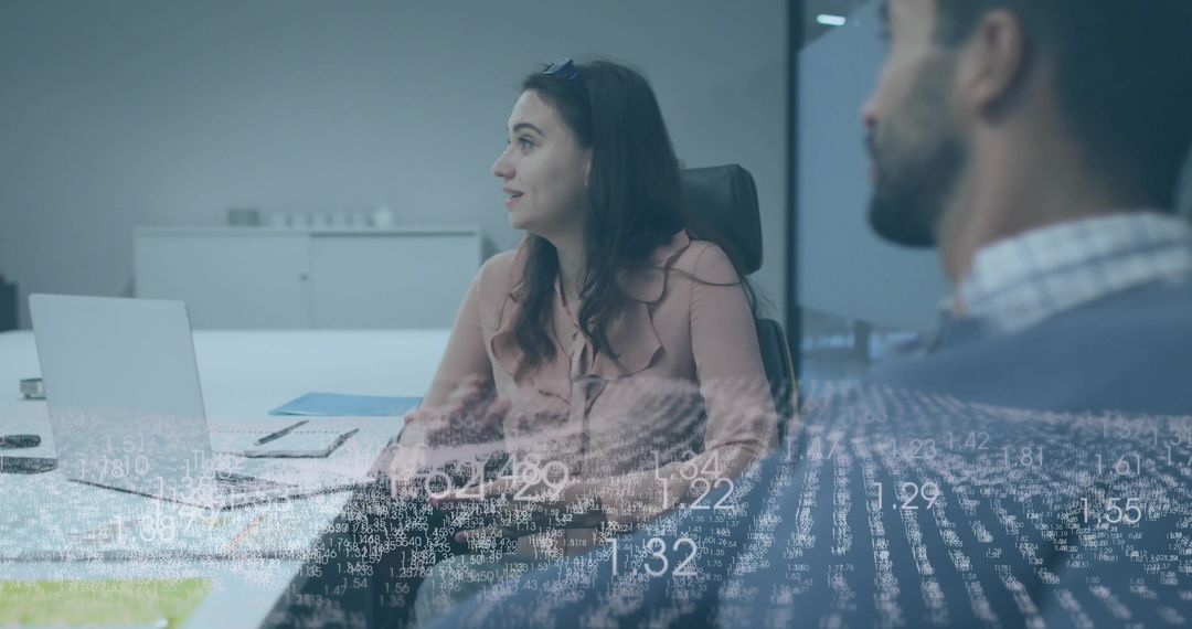 Professional team collaborating with woman gesturing at laptop during data-driven meeting