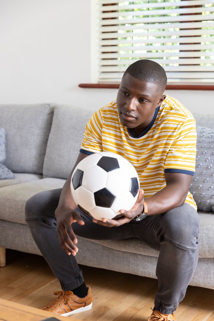 Young Man Contemplating at Home with Soccer Ball