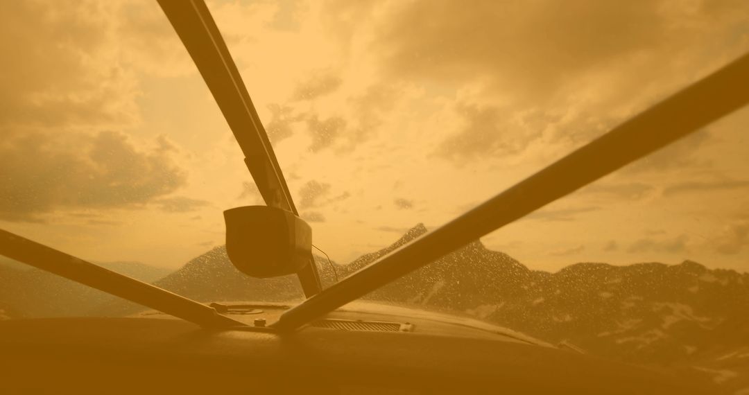 Cockpit Windshield View Over Mountain Range Showing Water Droplets and Golden Light