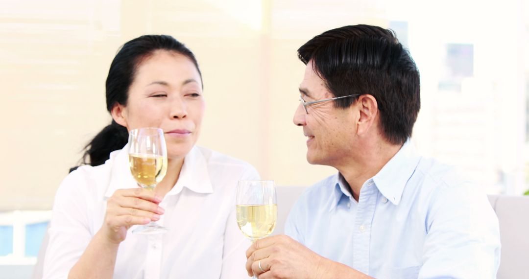 Senior Asian Couple Enjoying Glasses of White Wine Together - Free Images, Stock Photos and Pictures on Pikwizard.com