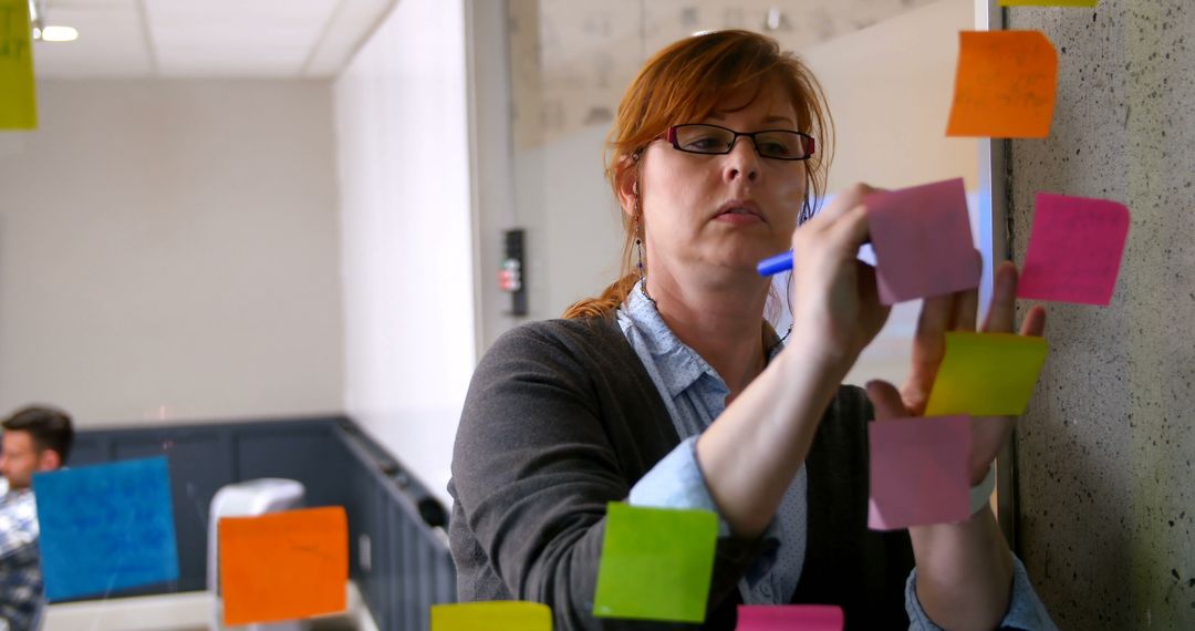 Businesswoman Writing on Sticky Notes During Office Meeting - Free Images, Stock Photos and Pictures on Pikwizard.com