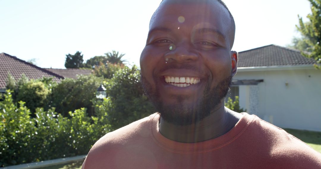 Joyful African American Man Smiling in Sunlit Garden - Free Images, Stock Photos and Pictures on Pikwizard.com