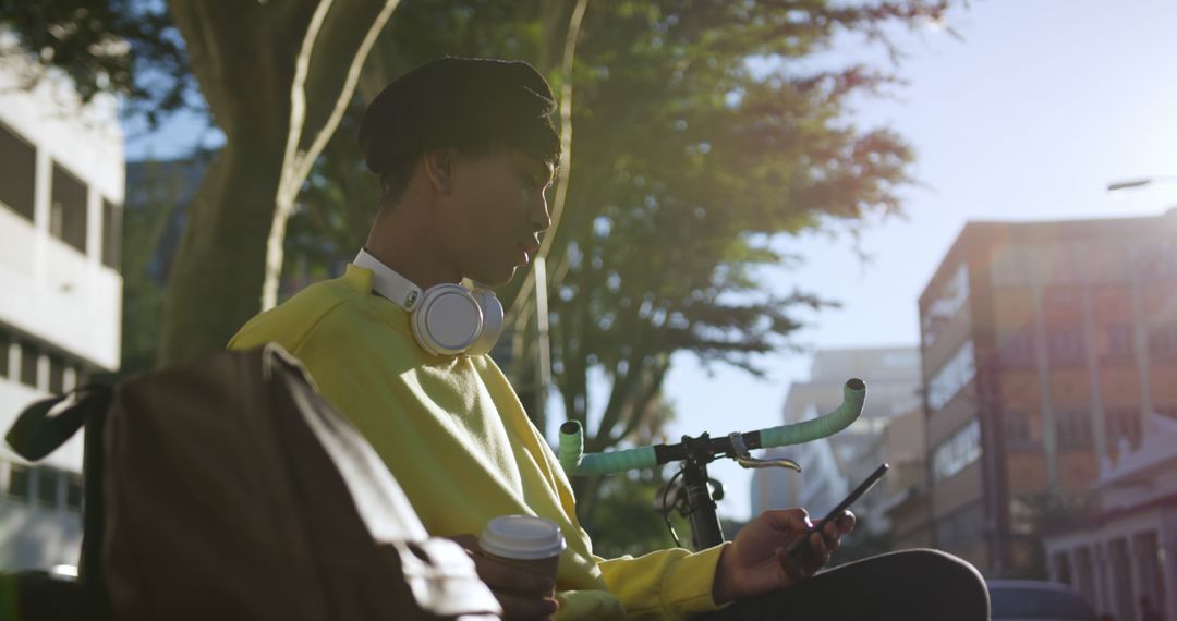 Young man with headphones using smartphone and drinking coffee outdoors - Free Images, Stock Photos and Pictures on Pikwizard.com