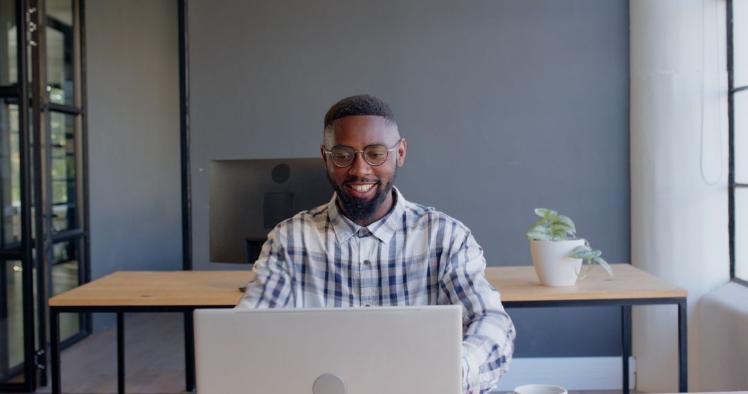 African American Man Smiling While Using Laptop at Office Desk