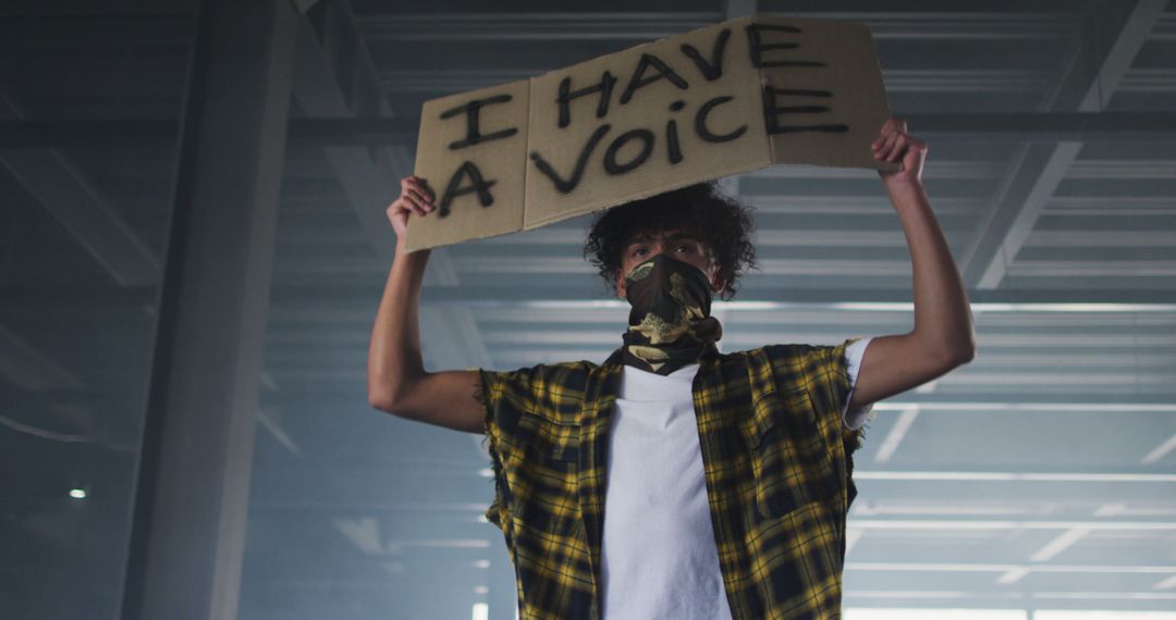 Young Activist Holding Protest Sign in Industrial Space - Free Images, Stock Photos and Pictures on Pikwizard.com