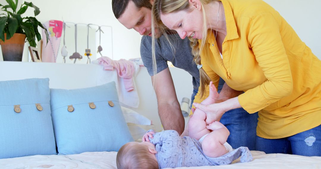 Parents Changing Baby Diaper on Bed in Cozy Nursery - Free Images, Stock Photos and Pictures on Pikwizard.com