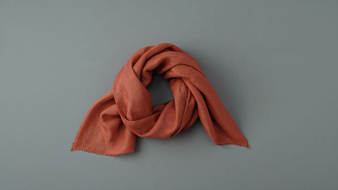 Rust-Colored Scarf Display on Gray-Blue Surface