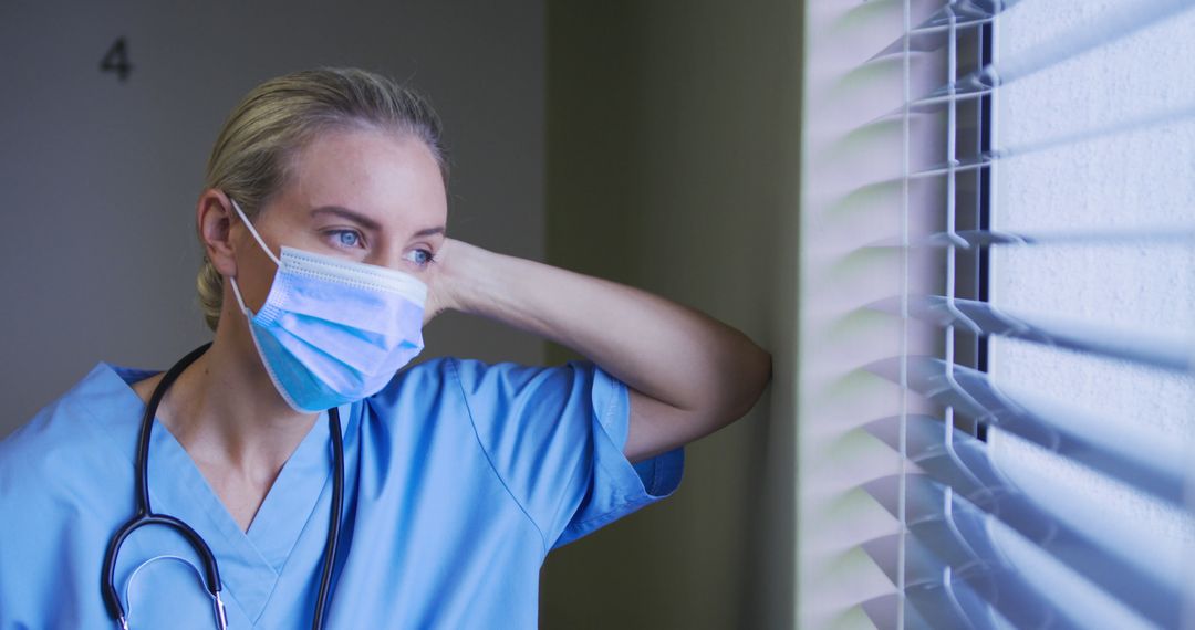 Portrait of caucasian female doctor wearing face mask looking through the window in hospital room - Free Images, Stock Photos and Pictures on Pikwizard.com