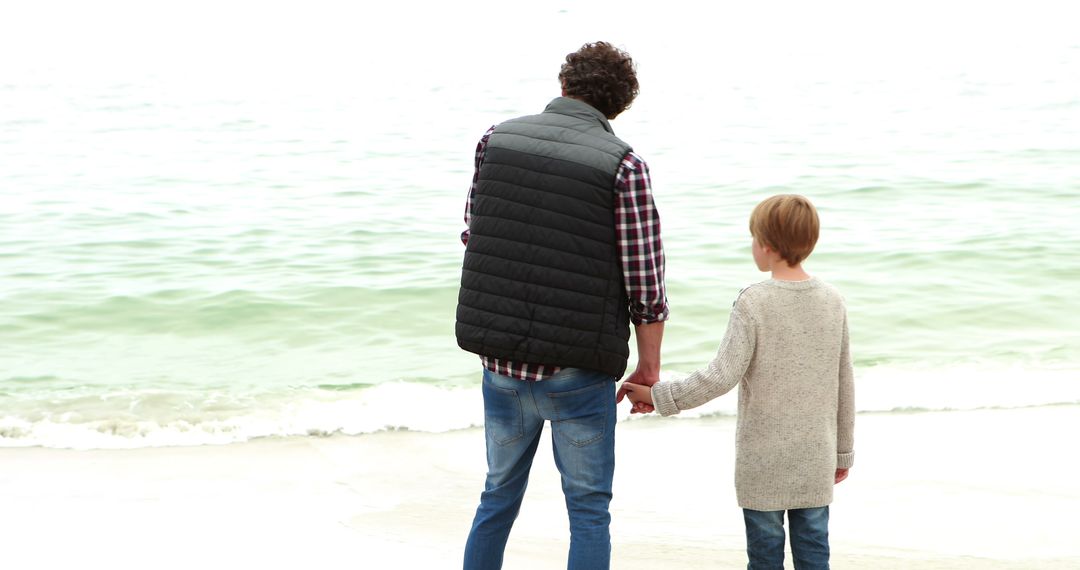 Father and Son Holding Hands While Strolling Along Beach - Free Images, Stock Photos and Pictures on Pikwizard.com