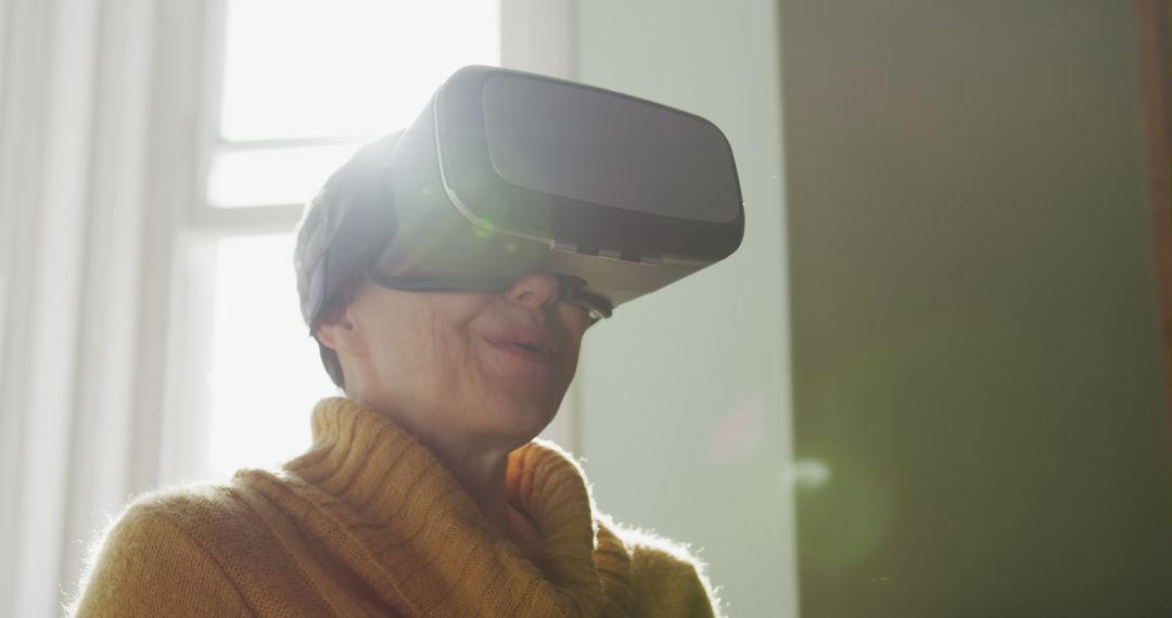 Senior woman experiencing virtual reality with VR headset in bright room - Free Images, Stock Photos and Pictures on Pikwizard.com