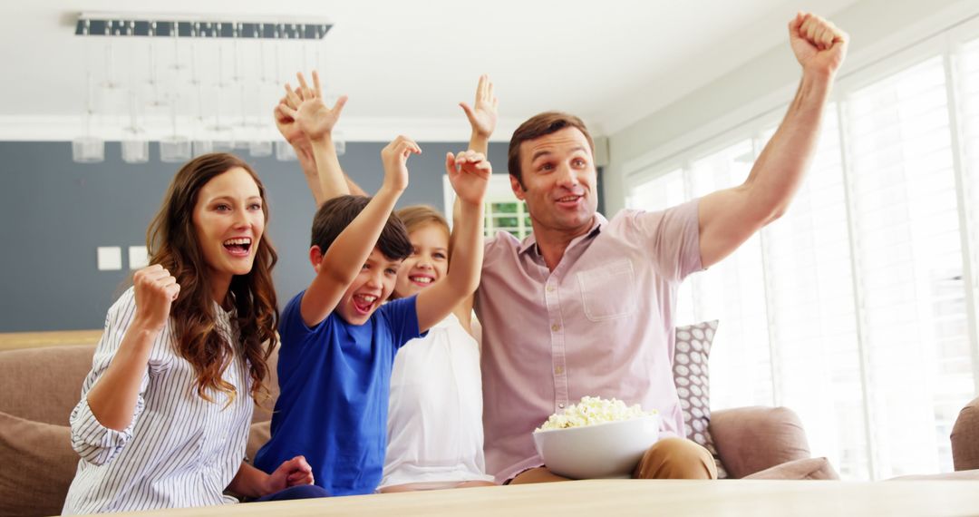 Excited Family Cheering and Eating Popcorn on the Couch - Free Images, Stock Photos and Pictures on Pikwizard.com