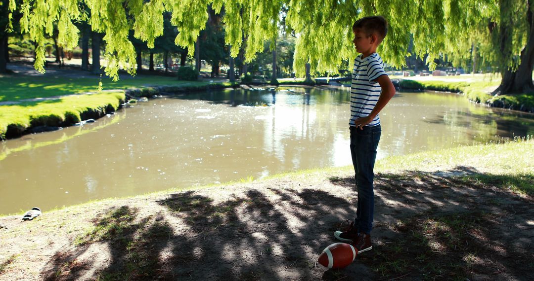 Young Boy Pondering by Lakeside Path Under Willow Trees - Free Images, Stock Photos and Pictures on Pikwizard.com