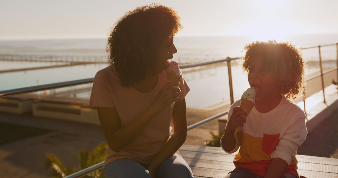 Mother and Child Sharing Ice Cream on Beach Boardwalk at Sunset - Free Images, Stock Photos and Pictures on Pikwizard.com