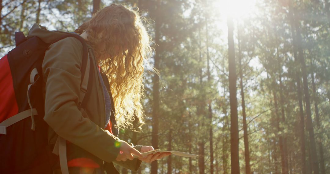 Young Woman Hiking and Navigating with Map in Sunlit Forest