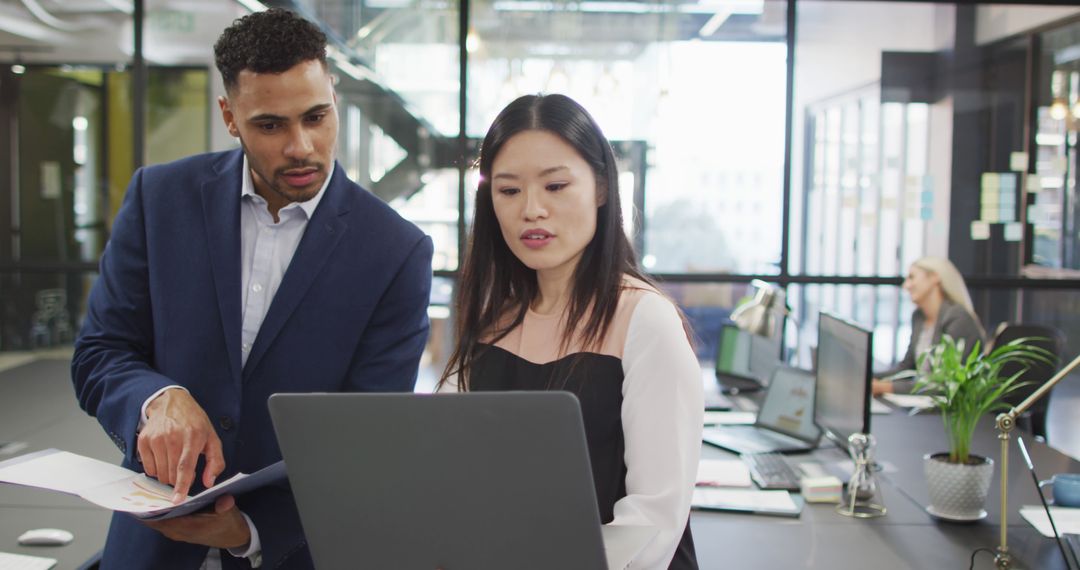 Diverse Colleagues Collaborating in Modern Office with Laptop