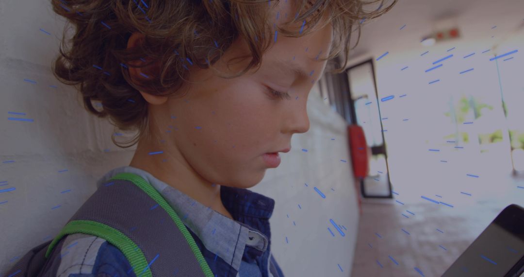 Leaning Child Checking Handheld Device in School Corridor With Backpack and Daylight
