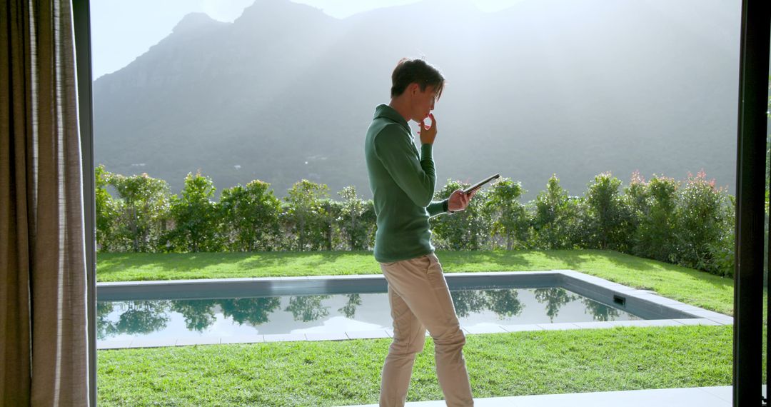 Man with Tablet in Modern Home by Tranquil Pool View