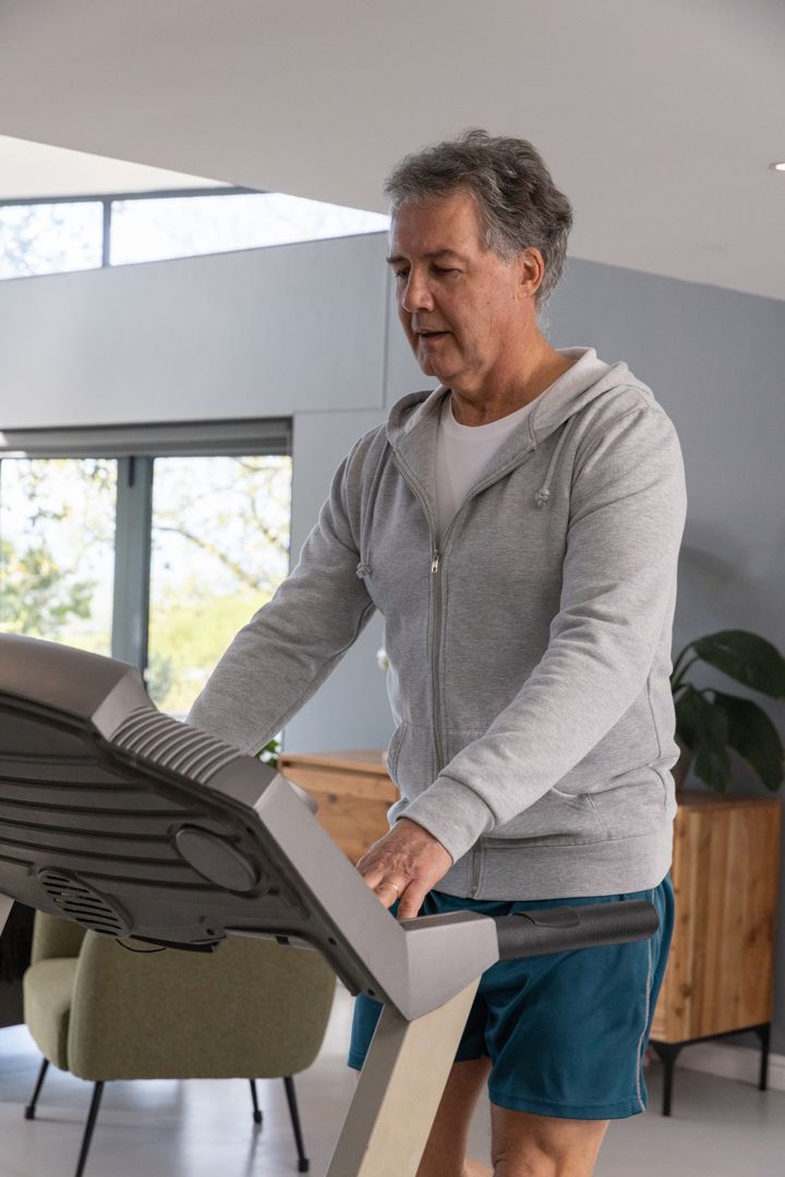 Man Adjusting Treadmill Settings in Modern Home Gym