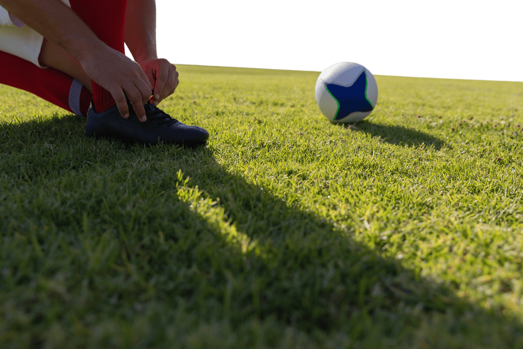 Athlete Tying Laces on Sports Field Creating Dynamic Shadows