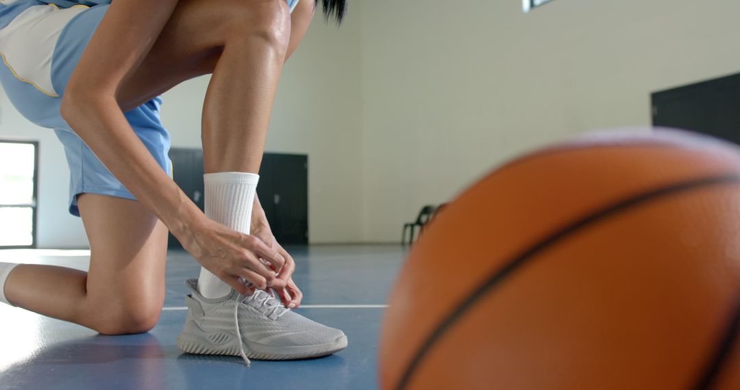 Female Athlete Tying Sneakers on Basketball Court