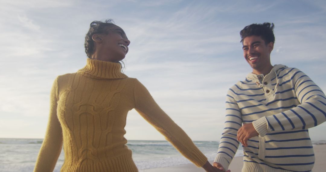 Joyful Couple Relaxing on Beach in Cozy Sweaters