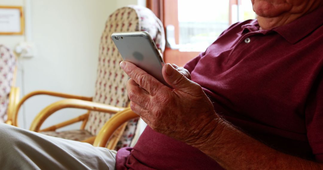 Senior Man Engaging with Smartphone in Relaxed Home Environment